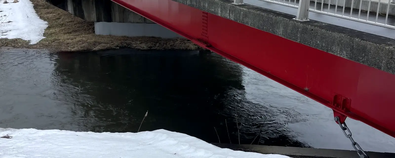 雪の川にかかる赤い橋